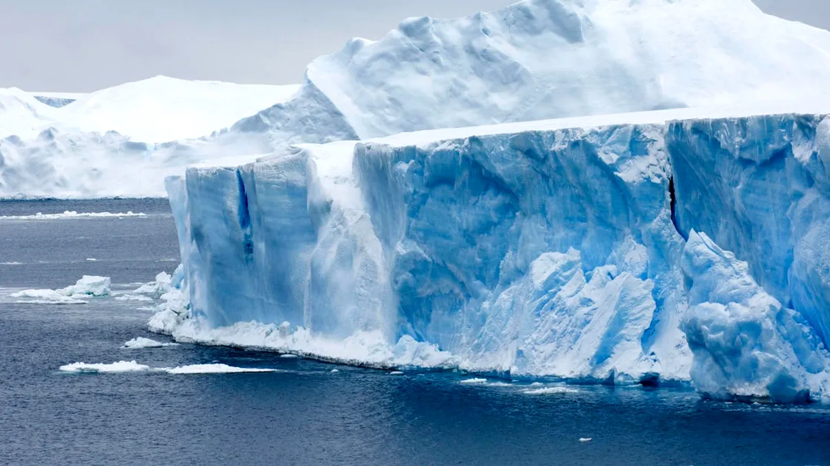 Momentul incredibil în care un iceberg gigantic se rupe și se răstoarnă în apropierea unor turiști