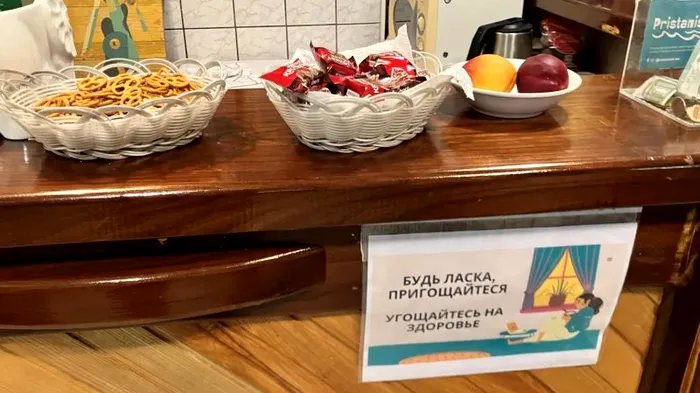 Un afiș bilingv în rusă și ucraineană la cafeneaua Pristaniște îi invită pe locuitori să se servească cu gustări.