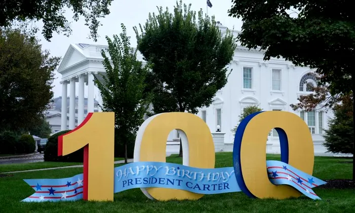 Un panou cu urarea „La mulți ani, Jimmy Carter, la împlinirea a 100 de ani” se află pe peluza nordică a Casei Albe din Washington DC