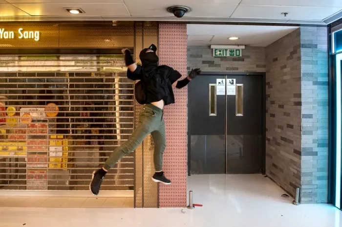 Un protestatar sare pentru a distruge o cameră de supraveghere în centrul comercial New Town Plaza din Hong Kong.
