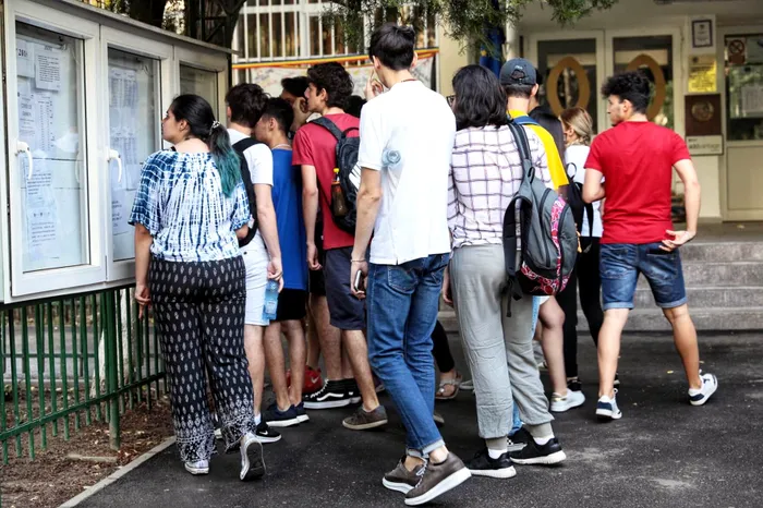 Elevi care se uită la un afișier.