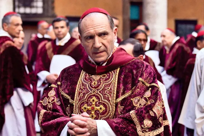 Ralph Fiennes interpretează cu subtilitate un cardinal prins între conștiință și putere, într-o poveste tensionată despre moralitate, secrete și compromisuri.
